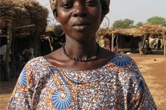 Afrikanische Frau vor einfachen Hütten.