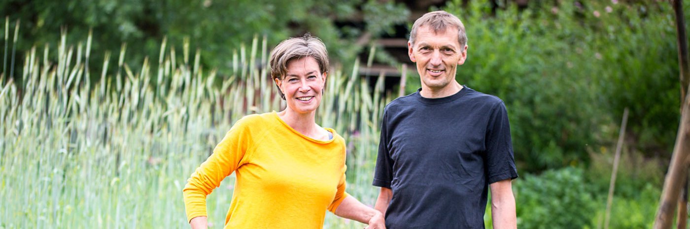Mann und Frau mit Schubkarre in einem Garten.