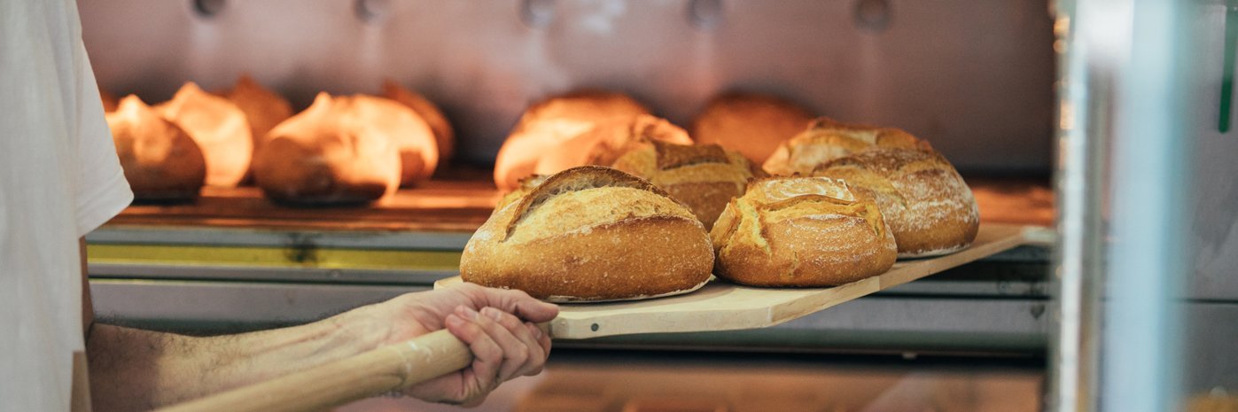 Brot wird aus einem Backofen geholt.