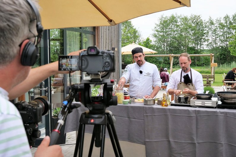 Kameramann filmt drei Menschen beim Kochen.