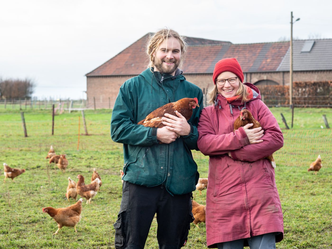 Mann und Frau mit Hühnern auf dem Arm