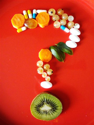 Aus Früchten, Gemüse sowie verschiedenen Tabletten ist ein Fragezeichen auf rotem Grund geformt.